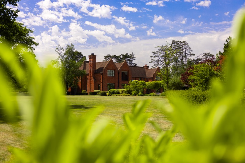 The house seen across the lawn through foreground planting